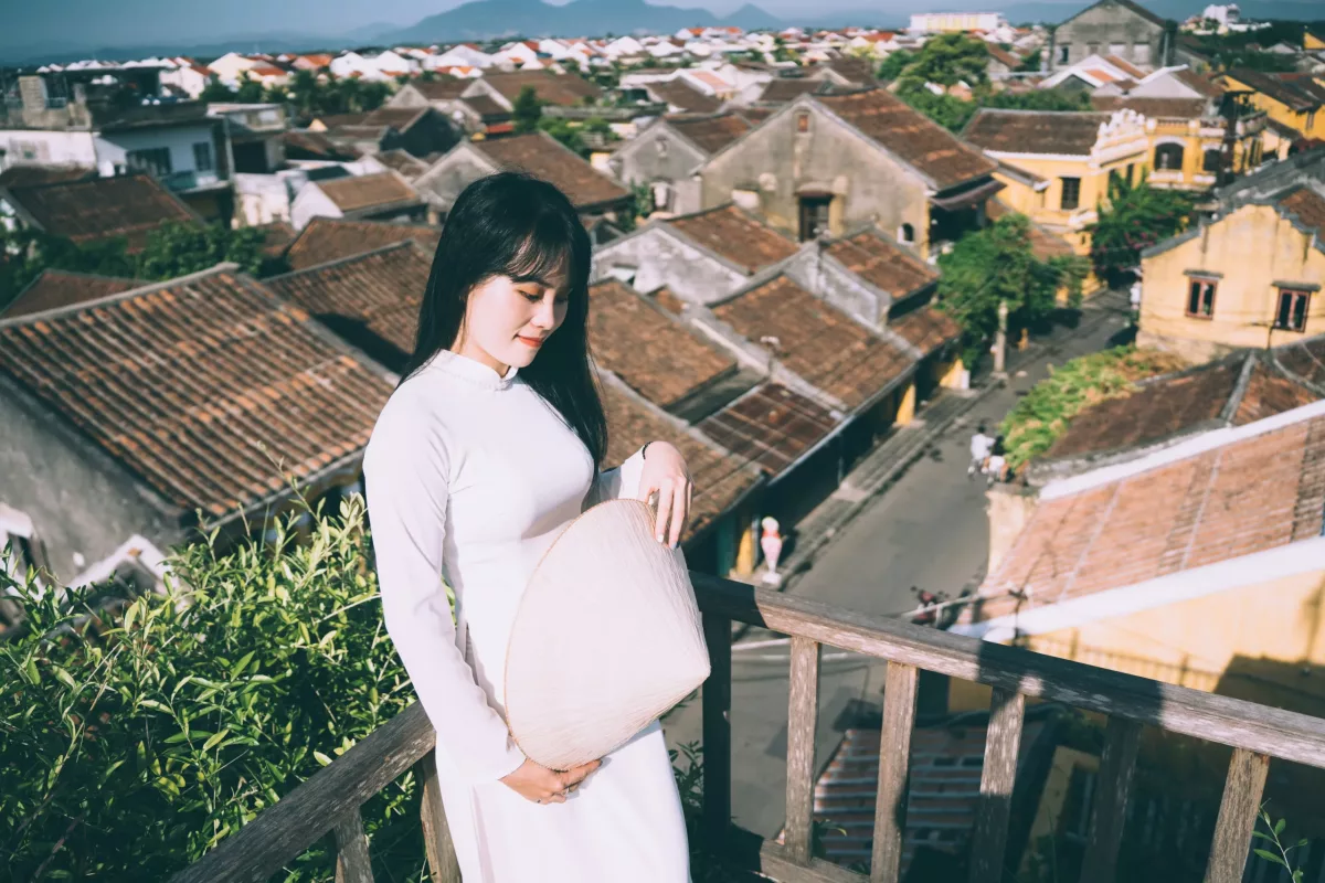 Femme asiatique brune avec robe blanche enceinte surpomlant la ville.