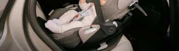 Bébé installé dans un siège auto Cybex Cloud T i-Size avec base Isofix, en position dos route dans une voiture moderne