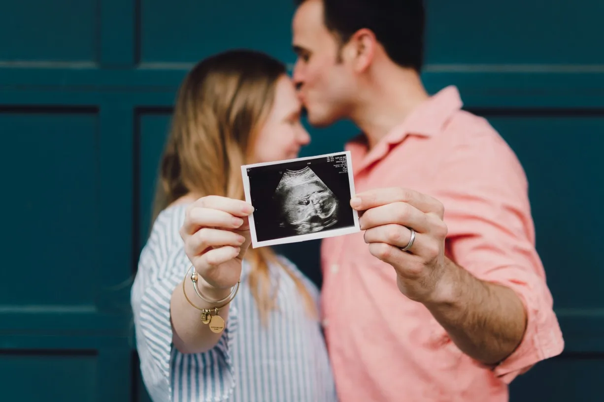 Un couple montre une photo d'une échographie avec leur bébé