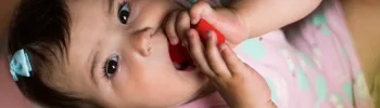 Bébé tenant un jouet coloré et le portant à sa bouche