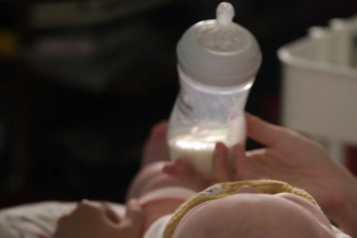 Parent proposant calmement un biberon à son bébé