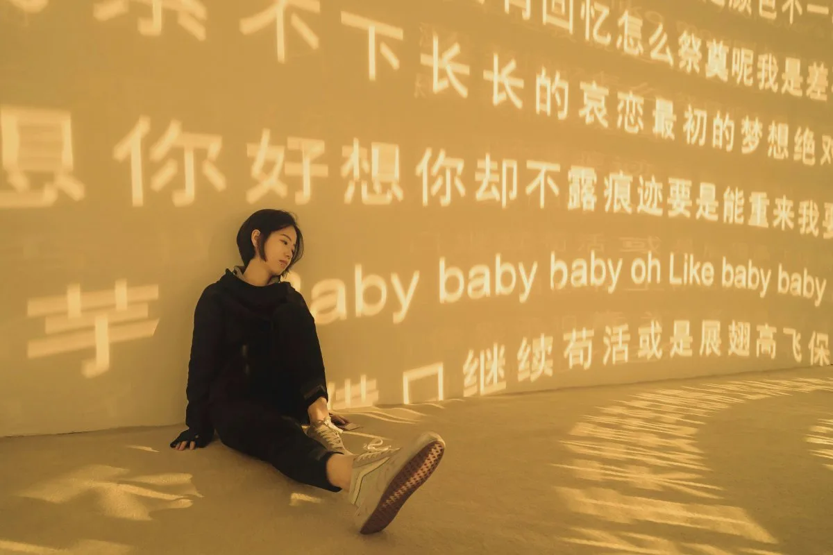 Femme assise devant un mur de caractères chinois évoquant le calendrier chinois grossesse