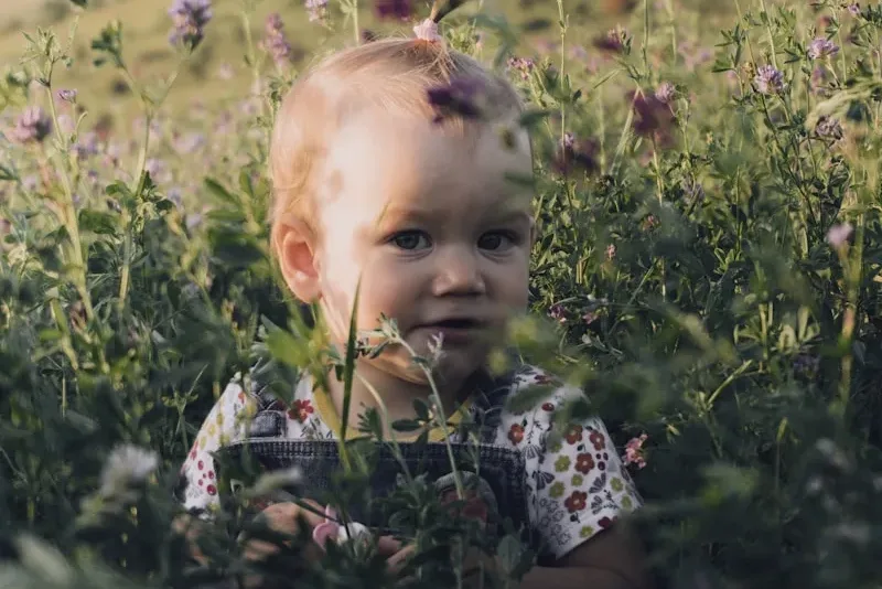 Jeune enfant dans un champ de fleurs au printemps, exposé aux pollens allergisants