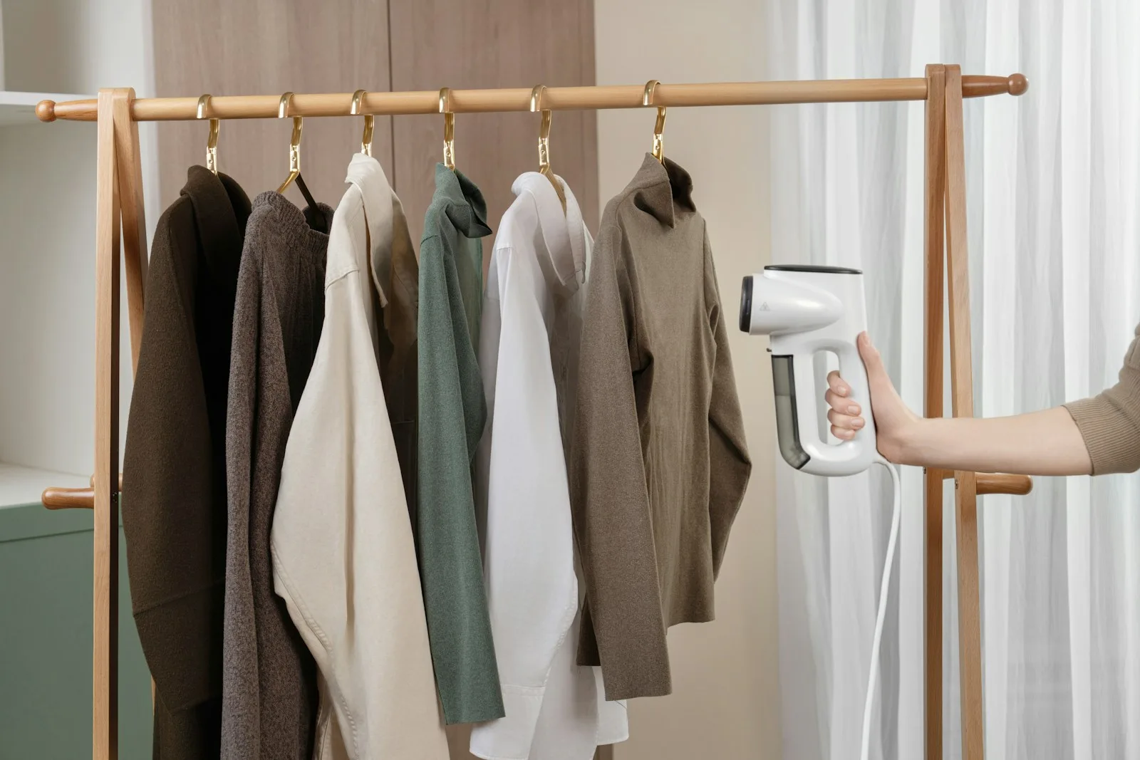 A woman is holding a dryer and ironing clothes