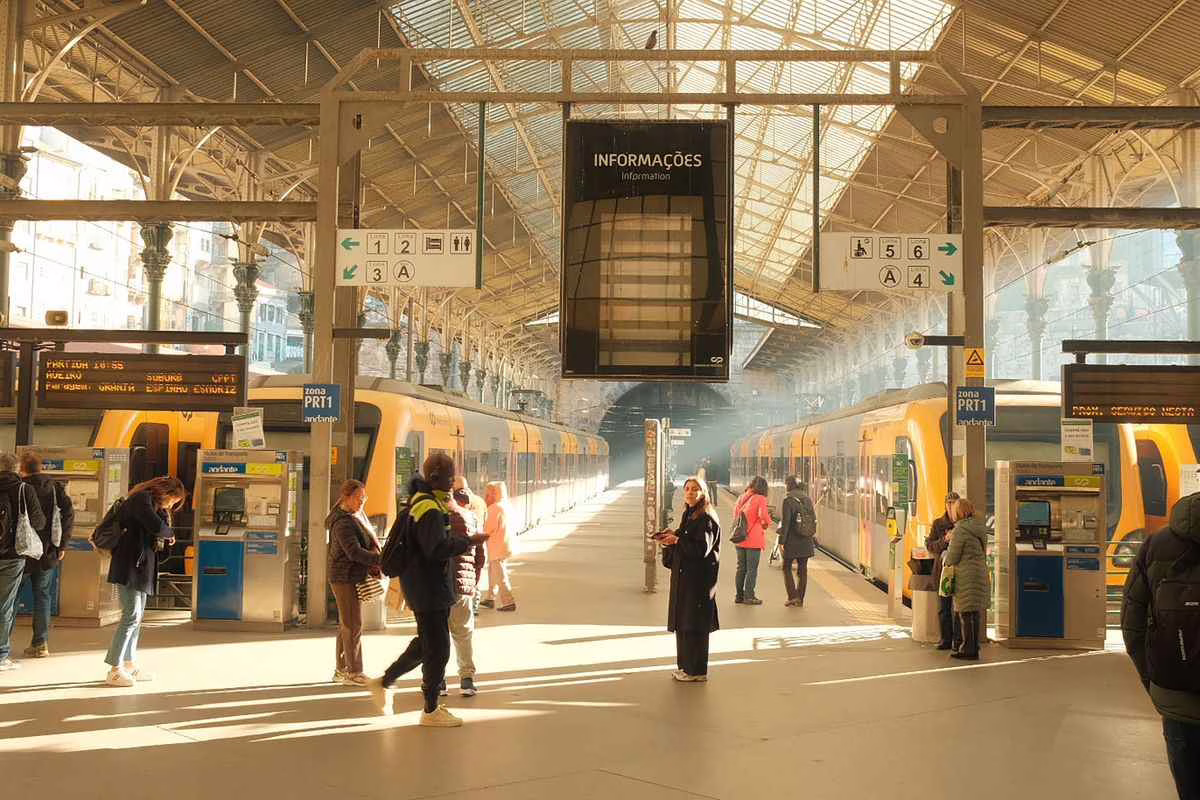 Famille avec plusieurs enfants et valises attendant le train sur un quai de gare en été