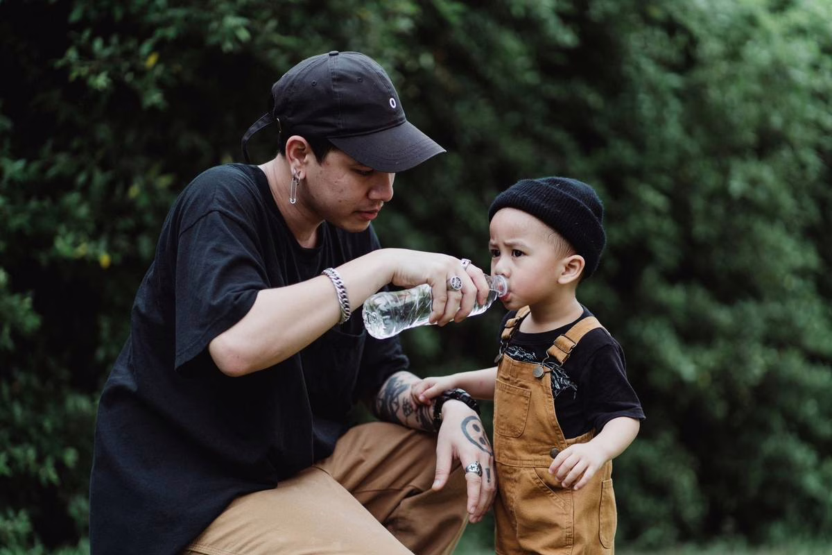 Parent donnant a boire de l eau a un jeune enfant en ete