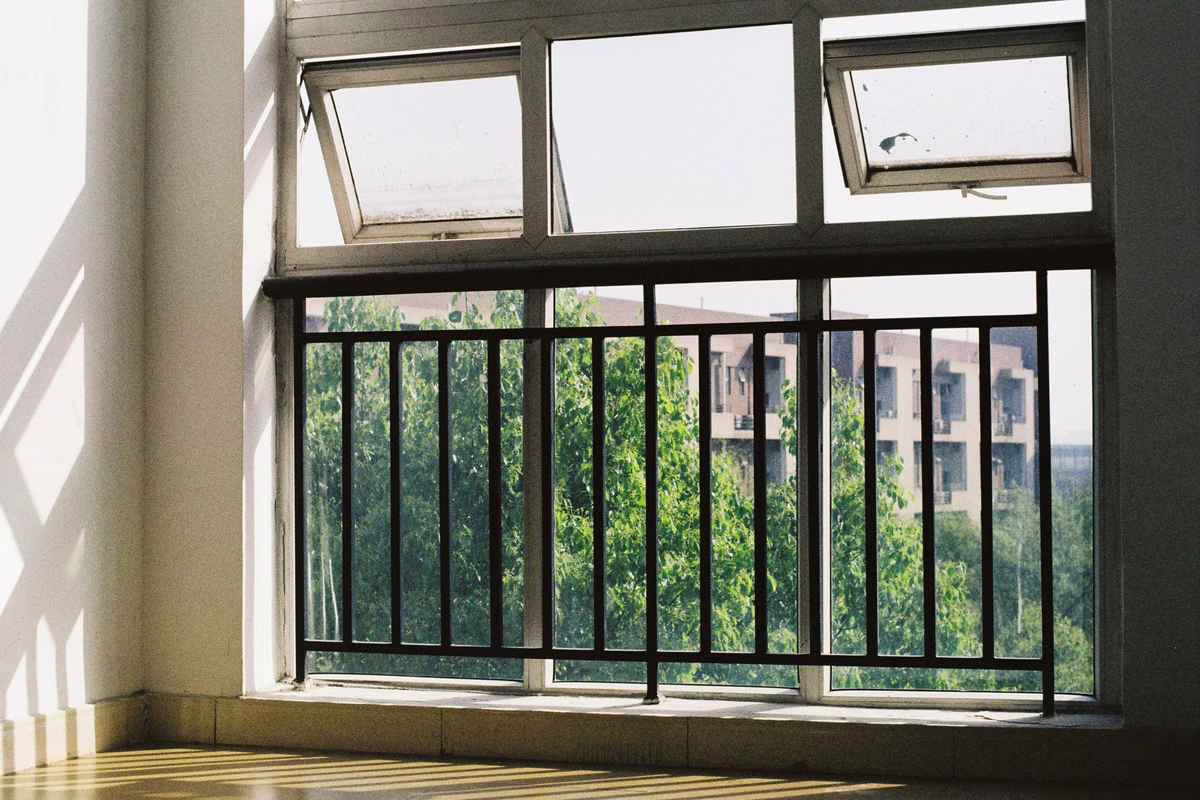 Fenêtre d'appartement ouverte avec un meuble bas à proximité, situation à risque de défenestration pour un jeune enfant