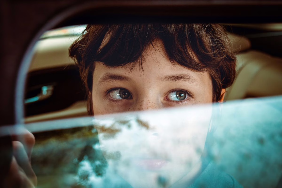 Un enfant regarde la route par la fenêtre de la voiture pendant un trajet, position qui réduit le mal des transports