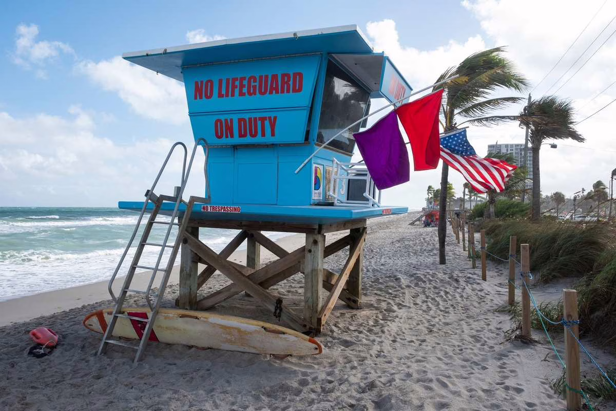 Drapeau de baignade rouge et jaune planté sur une plage surveillée près du poste de secours en été