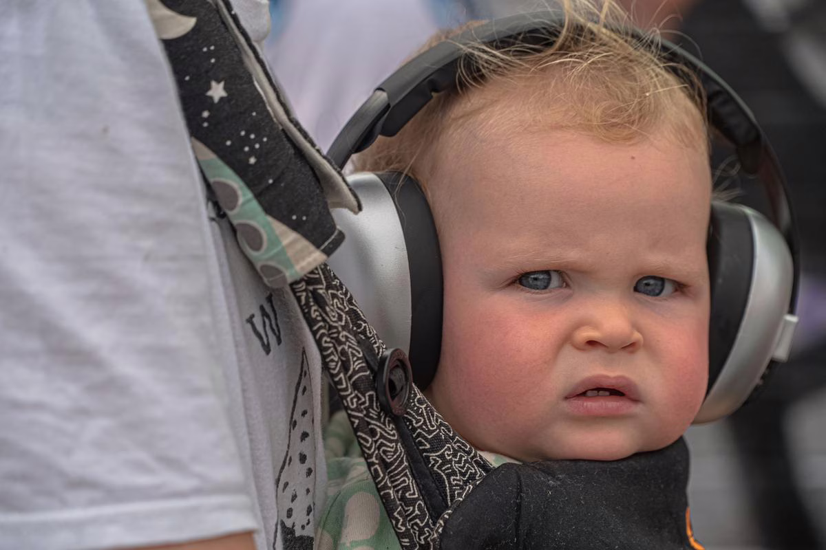 Jeune enfant portant un casque anti-bruit dans une foule en plein air pendant la fête de la musique
