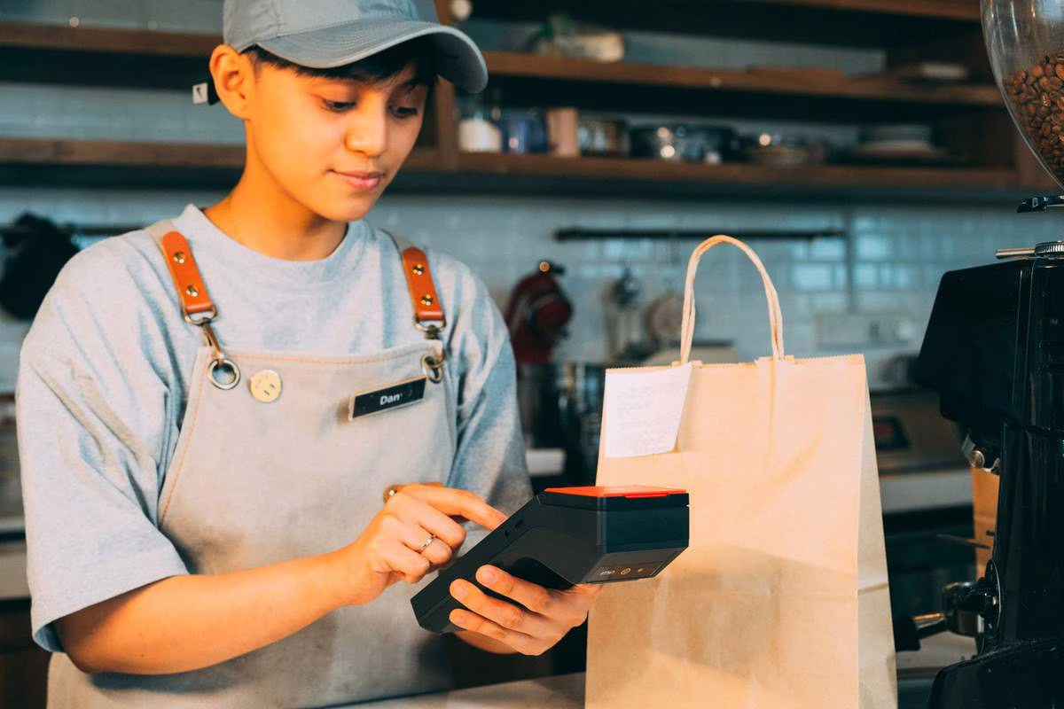 Adolescent au travail pendant son job d'été derrière un comptoir dans un commerce
