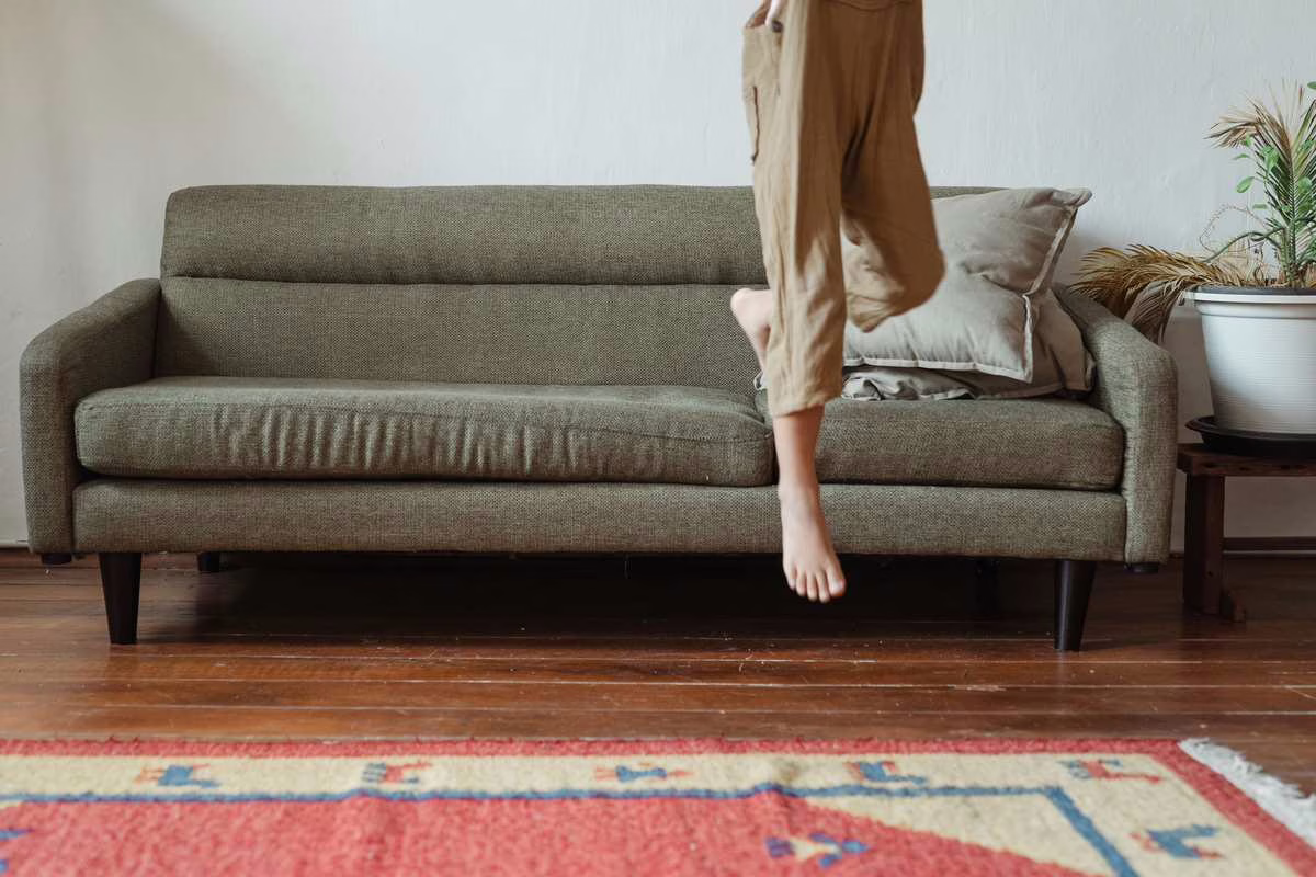 Enfant assis seul dans le salon de la maison, illustrant la question de l'âge pour laisser un enfant seul à la maison