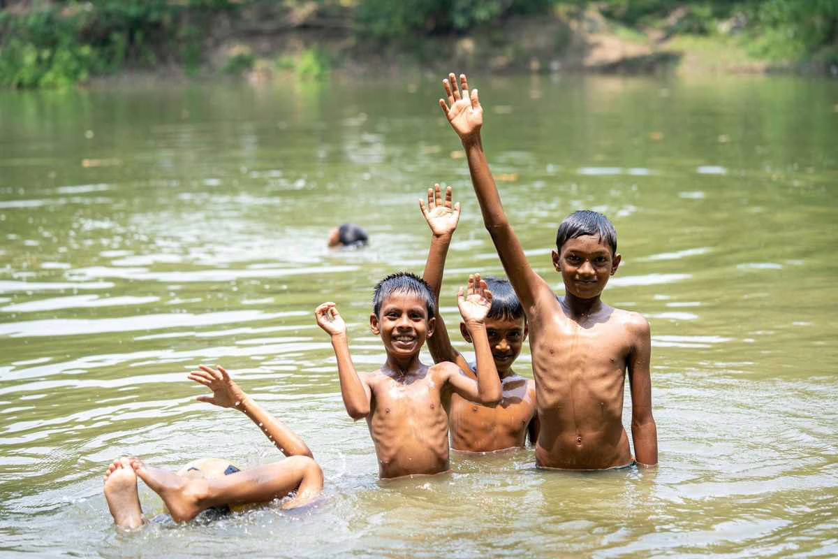 Enfants se baignant dans une rivière en eau douce l'été, contexte de prévention de la leptospirose