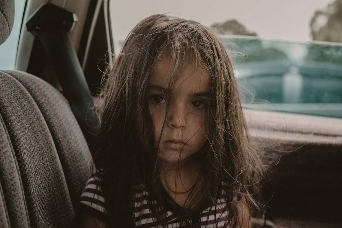 Jeune enfant attaché dans son siège auto regardant par la fenêtre pendant un long trajet en voiture l'été