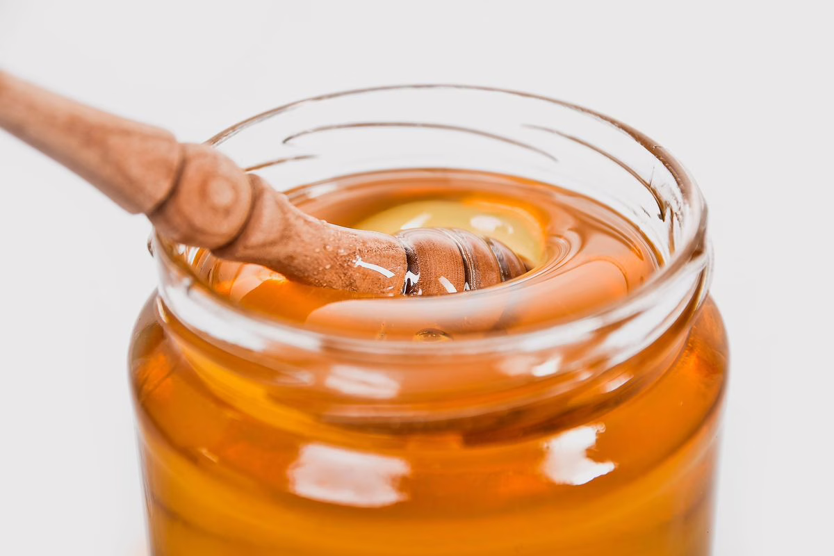 Pot de miel avec une cuillère en bois, un aliment à éviter pour un bébé de moins de 1 an