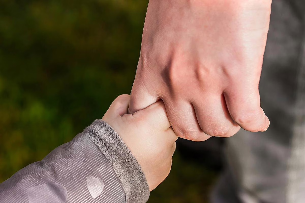 Un parent seul accompagnant son enfant à la maison, illustrant la question de la pension alimentaire après une séparation