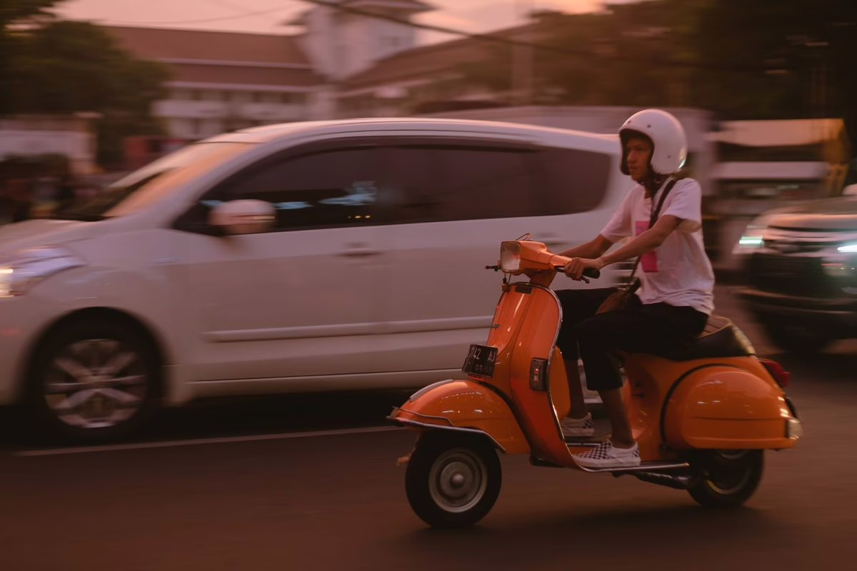 Adolescent conduisant un scooter avec un casque en ville, illustration du permis AM accessible dès 14 ans