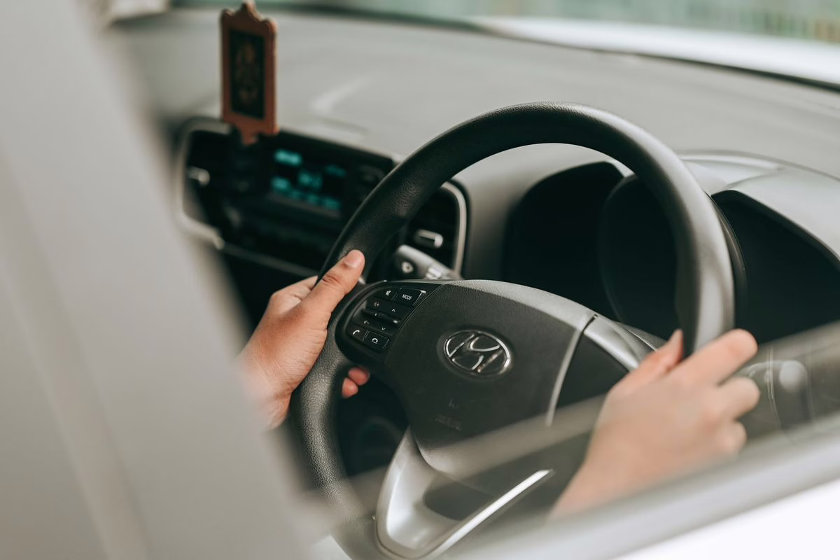 Mains d'un jeune conducteur tenant le volant, alors que plusieurs aides au permis de conduire disparaissent en 2026.