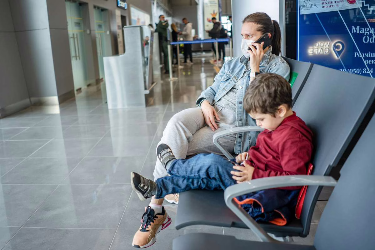 Parent portant un bébé dans un aéroport avant l'embarquement, préparation d'un voyage en avion avec un nourrisson