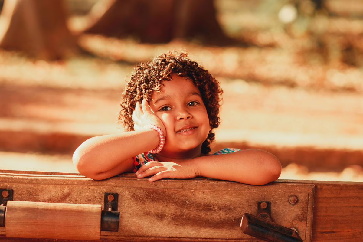 Petite fille africaine souriante en extérieur, illustration des prénoms africains pour fille
