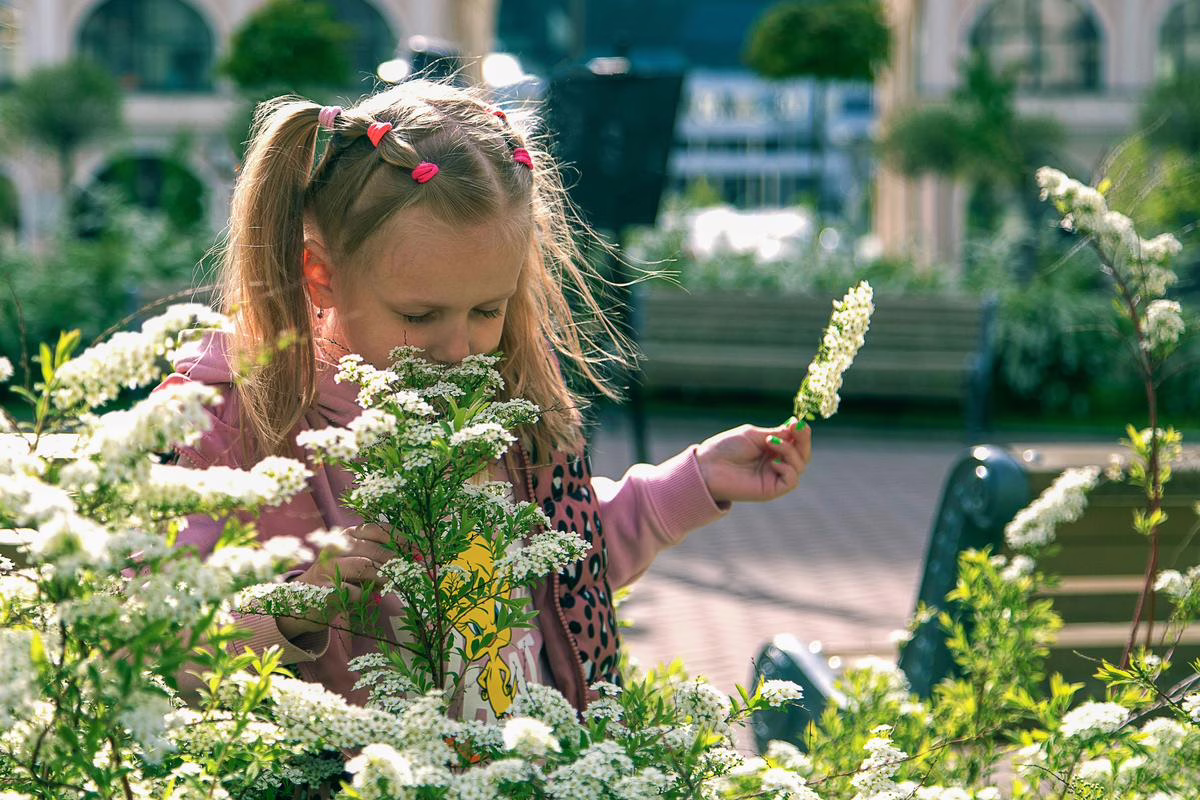 Petite fille tenant des fleurs dans un jardin, illustration des prénoms fleur
