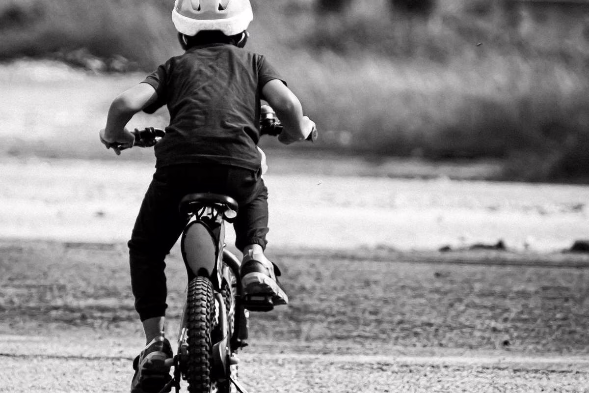 Un enfant installé dans un siège vélo enfant à l’arrière d’une bicyclette, casque sur la tête, lors d’une balade