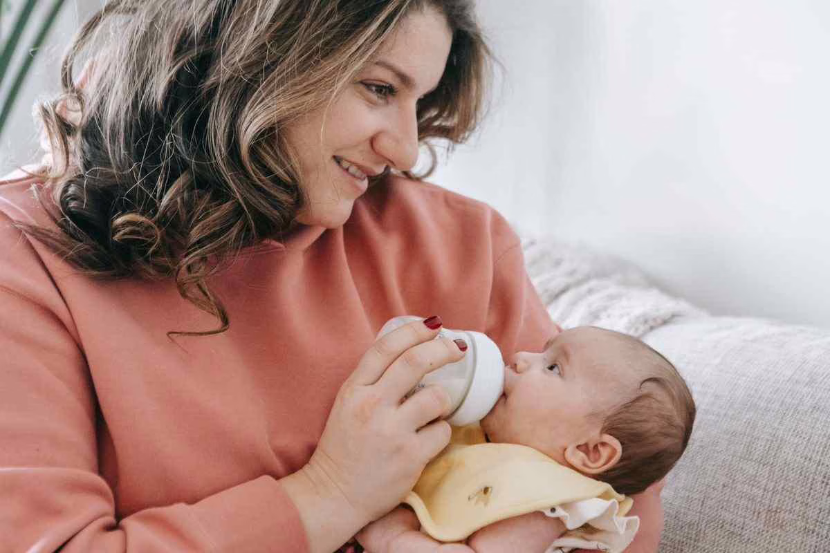 Parent qui donne un biberon réchauffé à son bébé, illustration des méthodes sans chauffe-biberon en vacances