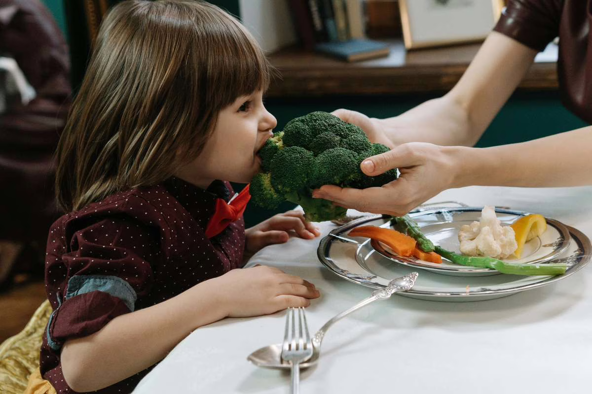 Assiette colorée de légumes, légumineuses et céréales devant un enfant, illustrant un régime végétarien équilibré