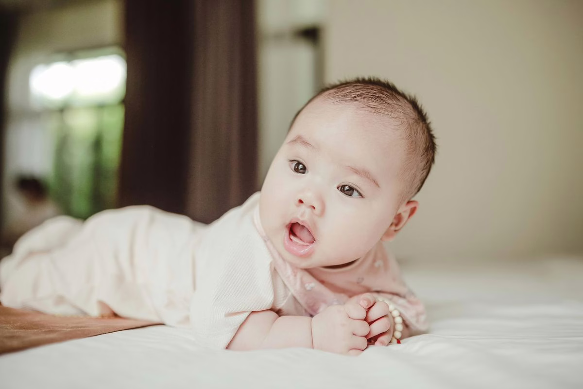 Bébé sur le ventre en éveil sur un tapis, exercice recommandé pour prévenir la tête plate ou plagiocéphalie
