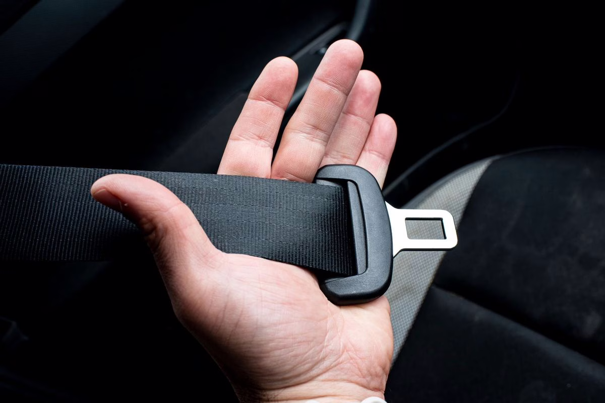Main bouclant une ceinture de securite en voiture, geste essentiel pour une femme enceinte lors d'un long trajet.
