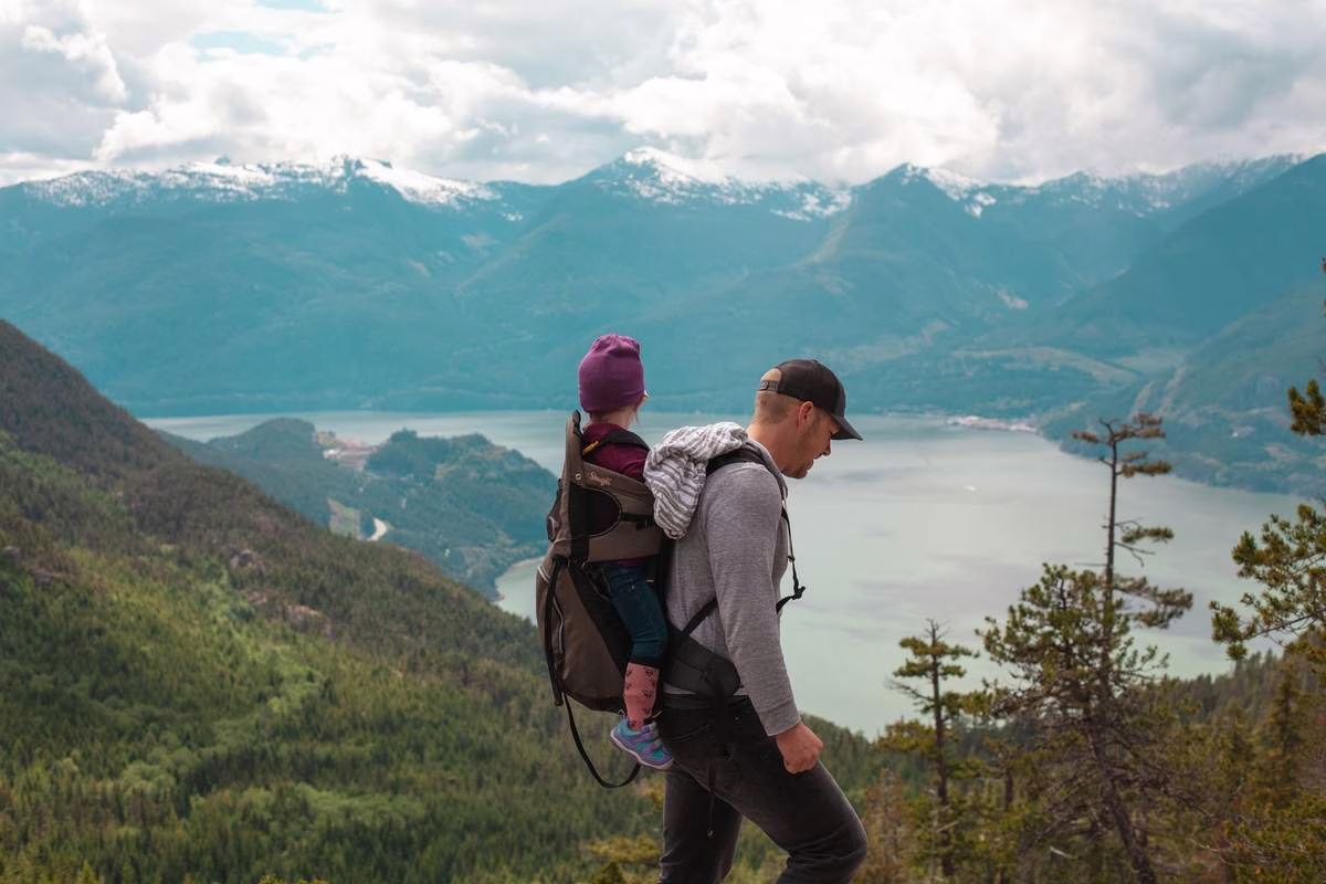 Parent portant un bebe en porte-bebe lors d'une randonnee en montagne l'ete