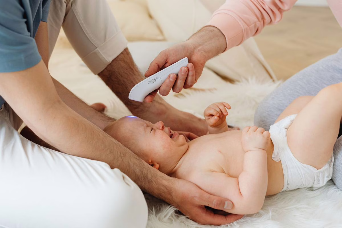 Parent qui prend la température d'un jeune enfant fiévreux allongé dans son lit