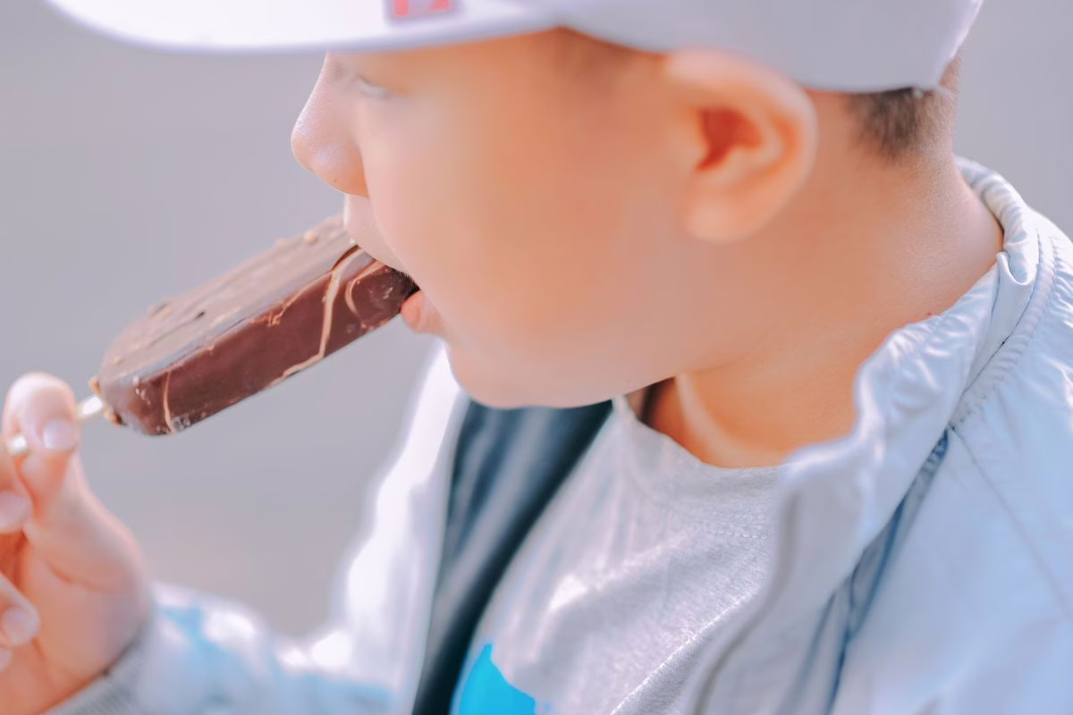 Jeune enfant dégustant une glace en été, un plaisir de saison à proposer avec quelques précautions