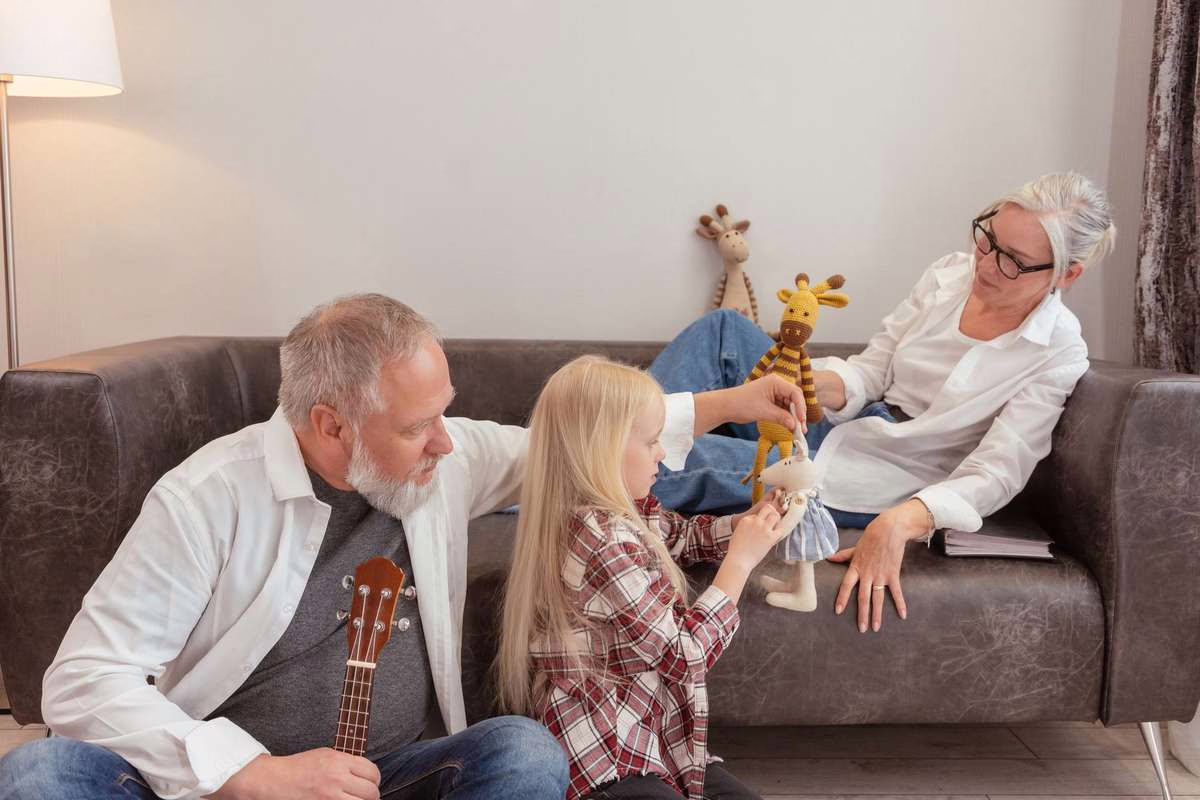 Grands-parents jouant avec leur petit-enfant dans le jardin familial pendant les vacances d'été