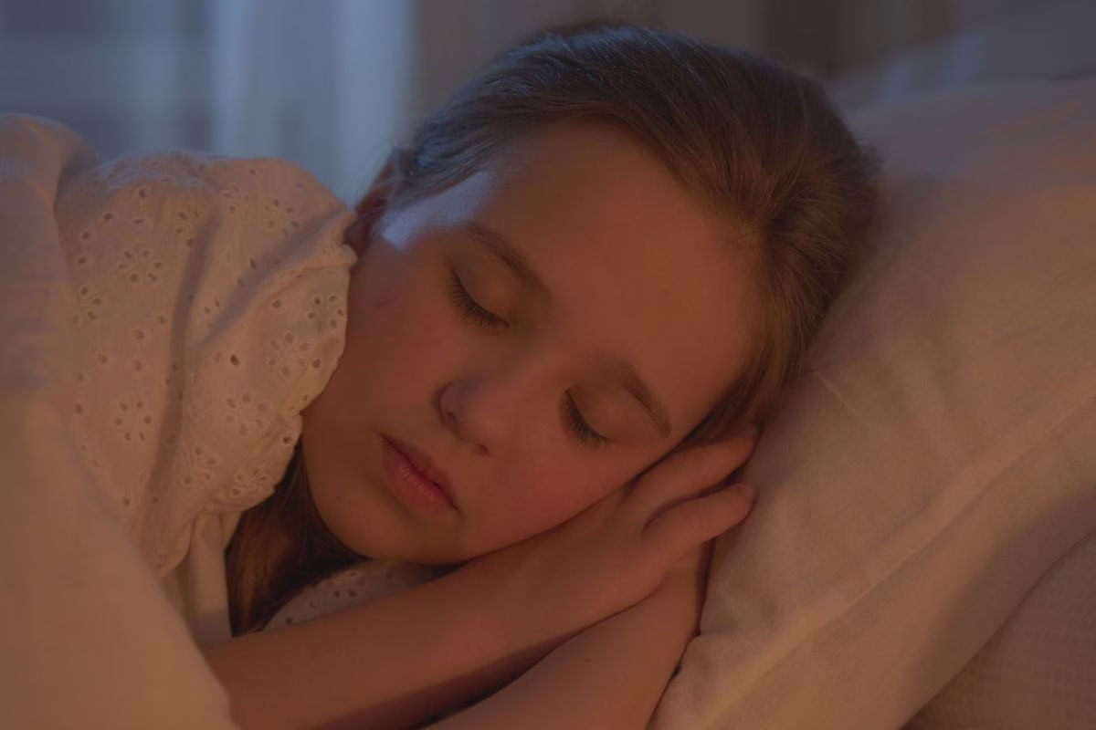 Enfant endormi paisiblement dans son lit avec une petite veilleuse douce en arrière-plan