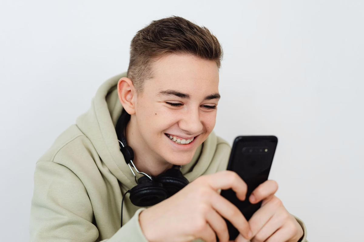 Adolescent qui consulte une application de reseau social sur son telephone dans sa chambre