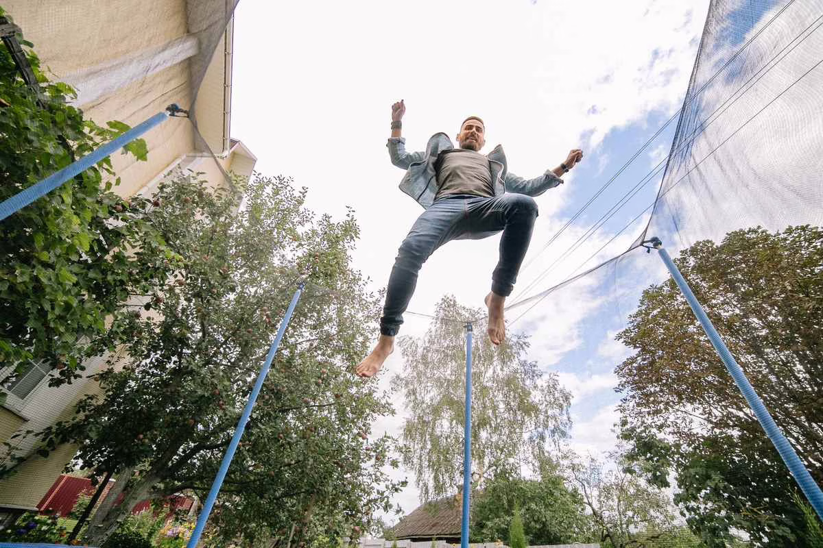 Trampoline de jardin équipé d'un filet de protection dans un jardin familial en été