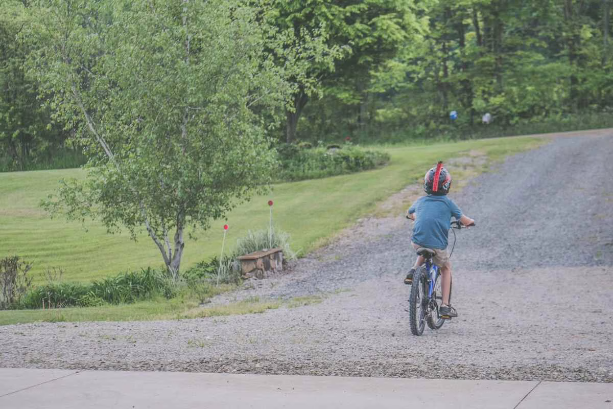 Enfant à vélo portant un casque bien ajusté sur une piste cyclable, conforme à l'obligation légale