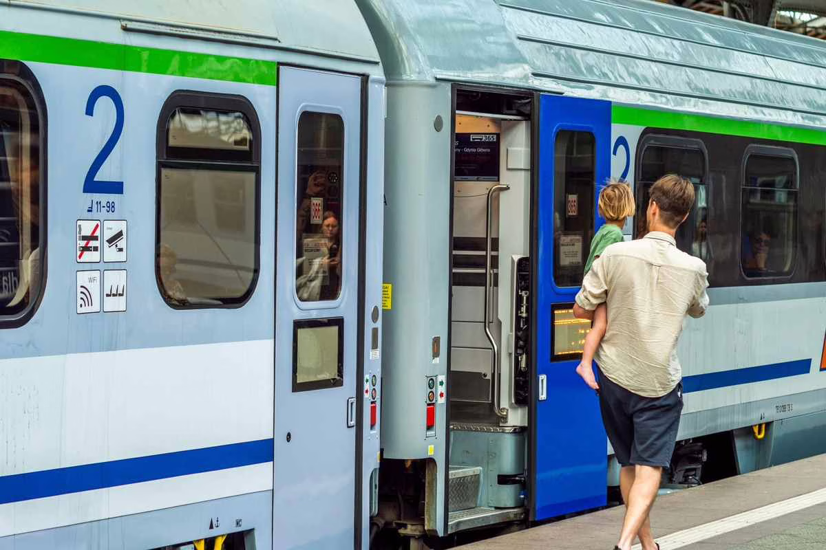 Parent avec une poussette et un bebe sur un quai de gare, illustrant un voyage en train