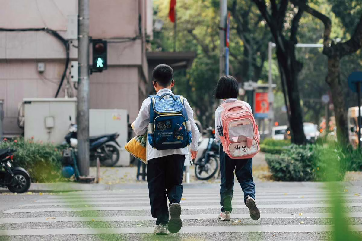 Un enfant marche seul sur un trottoir avec son cartable sur le chemin de l'école le matin