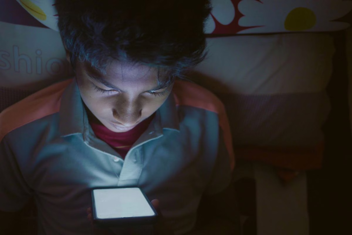 Adolescent qui regarde des vidéos sur son smartphone, où les contenus générés par IA doivent être signalés