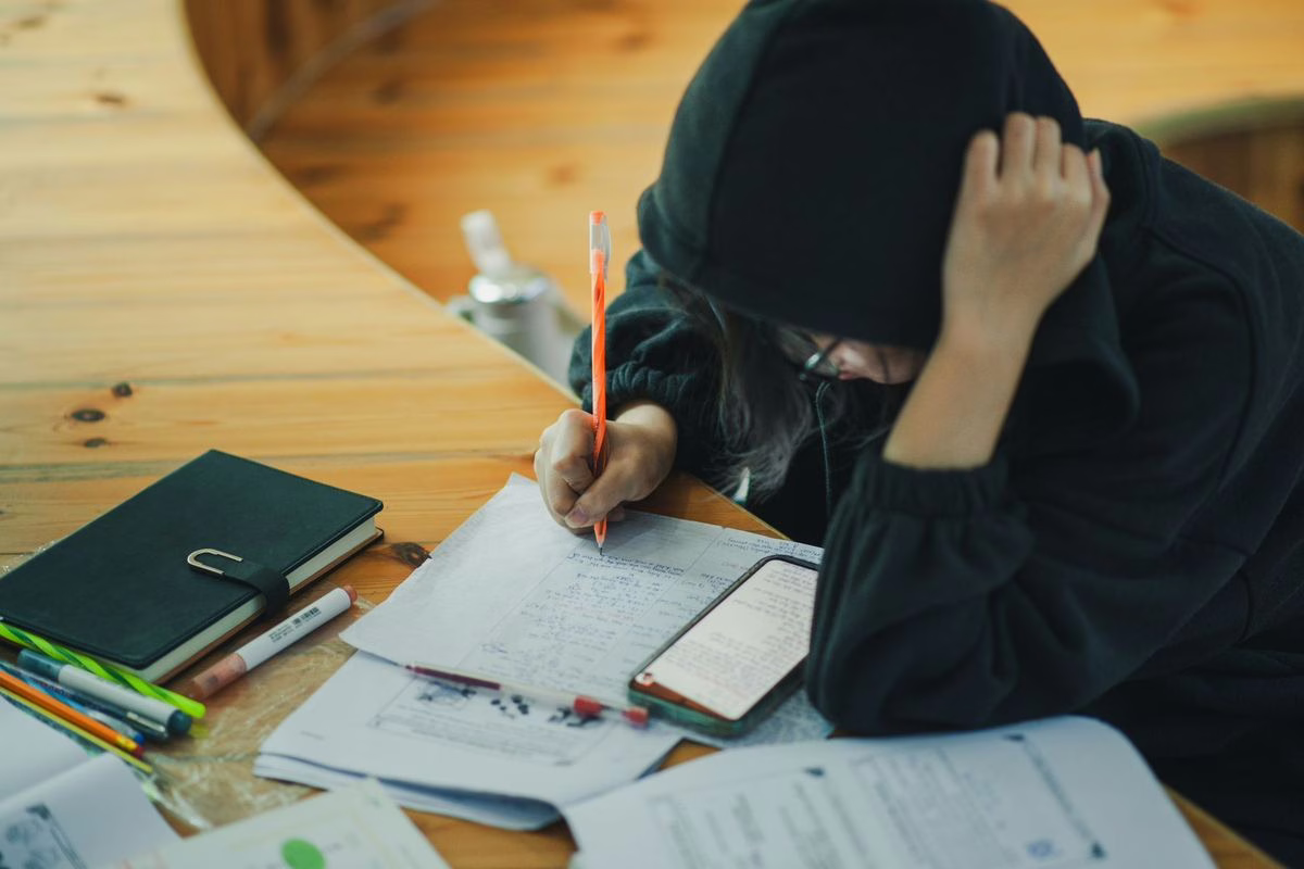 Des collégiens travaillent leurs devoirs autour de tables dans une salle d'étude encadrée par un adulte