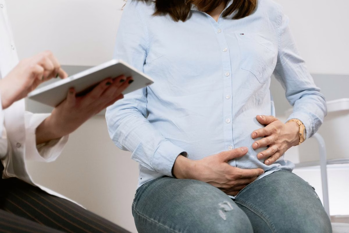 Femme enceinte en consultation avec une sage-femme, illustrant l’entretien prénatal précoce du quatrième mois de grossesse