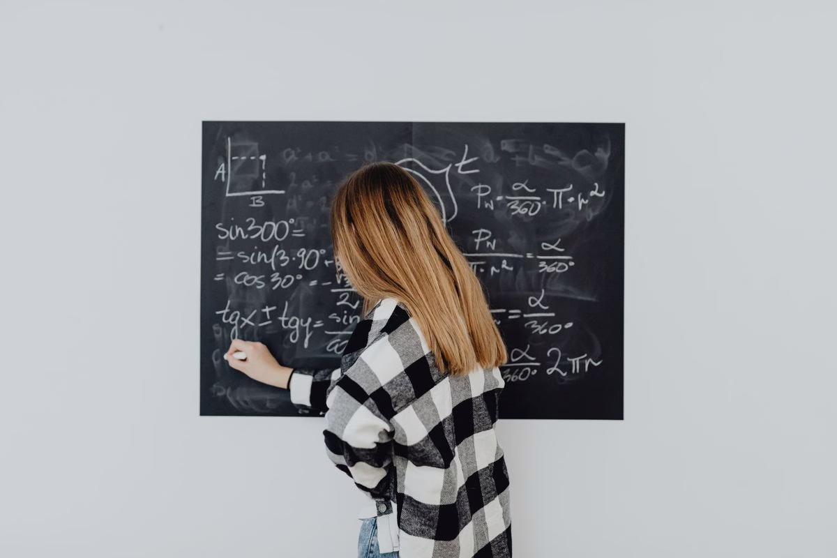 Une écolière résout un exercice de mathématiques sur son cahier à la table de la maison, crayon à la main
