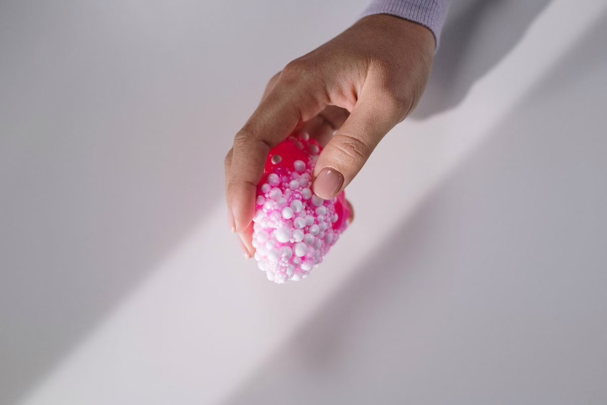 Main d'adulte tenant un jouet squishy rose à billes de mousse, illustration de l'alerte DGCCRF sur la sécurité des jouets antistress pour enfants