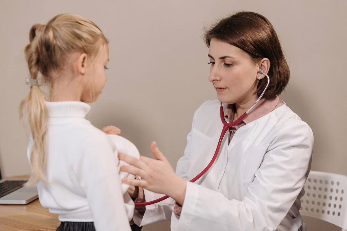 Pédiatre auscultant un jeune enfant en consultation, illustrant le suivi médical gratuit proposé par la PMI jusqu’à 6 ans