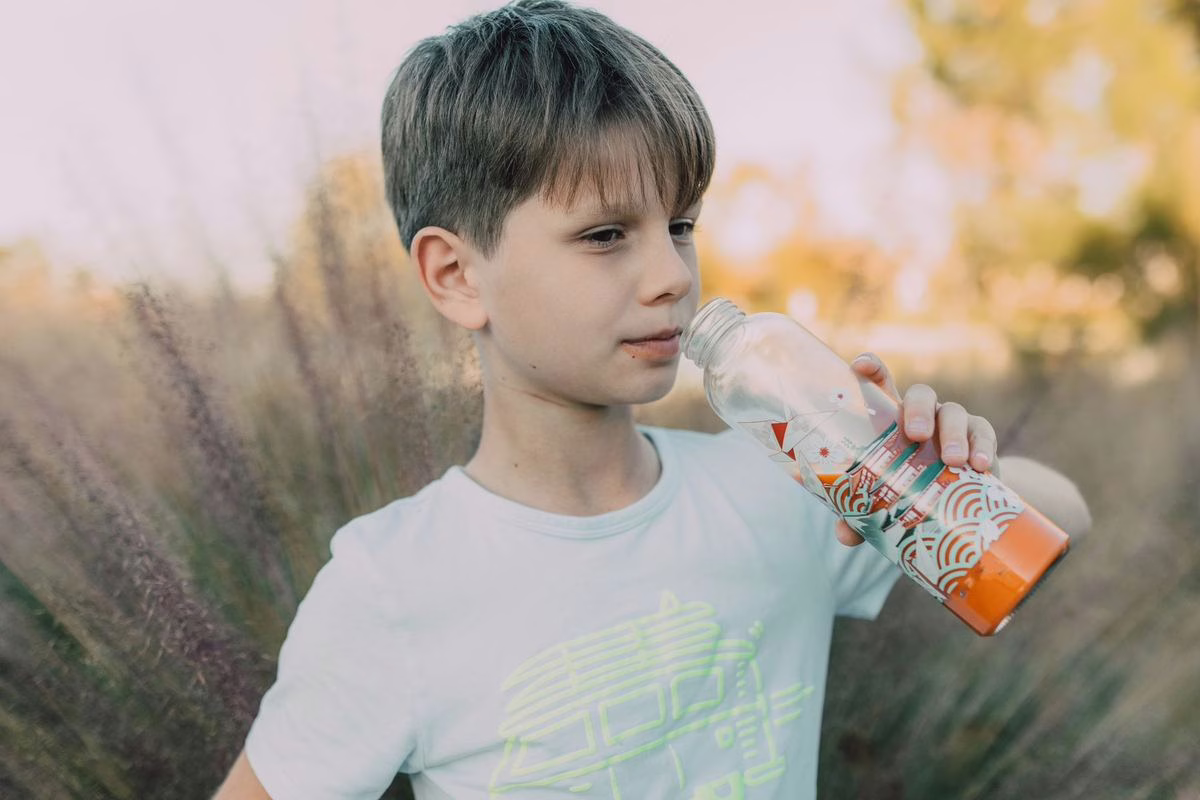 Enfant buvant à sa gourde en extérieur, illustration du rappel gourde Initiatives en aluminium 40 cl