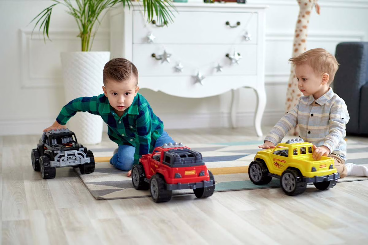 Deux jeunes enfants jouant avec des voitures jouets sur le sol du salon, illustration du rappel jouet Lamborghini publié sur RappelConso en août 2026