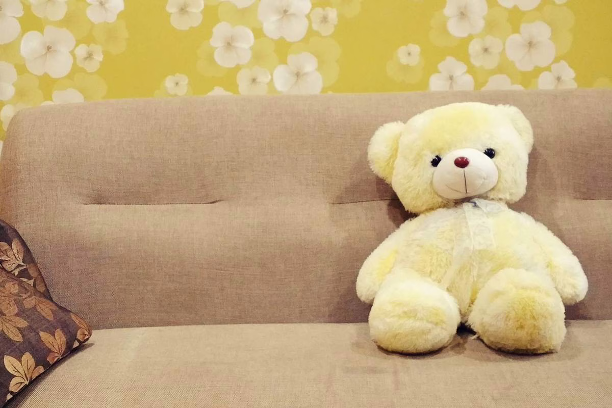 Peluche posée sur le lit d'un enfant dans une chambre, illustrant les rappels de jouets pour risque d'étouffement