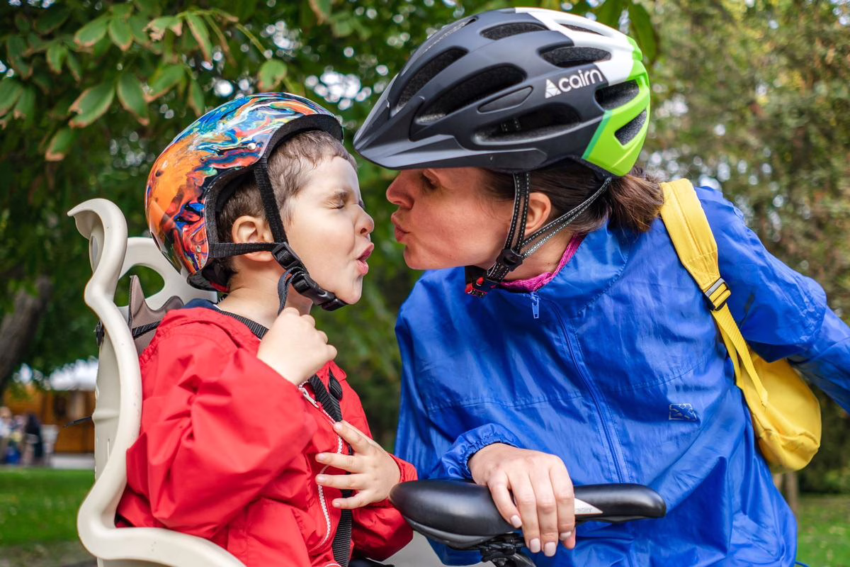 Enfant casqué installé sur un vélo et parent portant un casque, obligation légale avant 12 ans